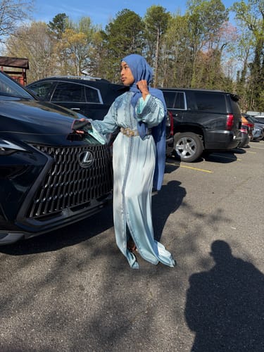Reviewer standing outdoors in the light blue, silky Caftan Maisa.