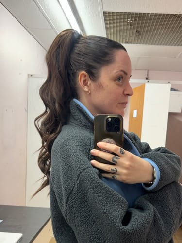 A reviewer seen from the side, wearing the long, wavy Stranded clip-in ponytail.