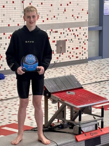 Customer wearing the black Youth Oversized Hoodie while holding a swim meet trophy by a pool.