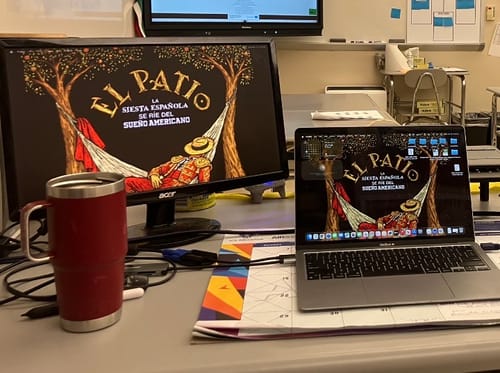 Reviewer's desk showing the LA SIESTA WALLPAPER used on both a large monitor and a laptop screen.