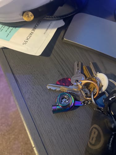 Customer's iridescent Turbo Keychain attached to a set of keys on a dark surface.