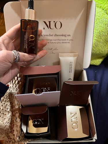 Reviewer holding the brown glass Ser cu Vitamina C bottle over an open package containing other products.