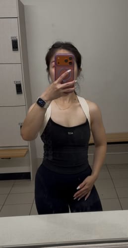 Reviewer in a locker room mirror selfie wearing the black Sculpt Tank, showing its flattering fit and ruched sides.