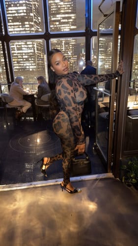Customer showing the side profile and bodycon fit of the leopard print Naked Print Stirrup Jumpsuit.