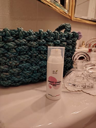 Recensore mostra il flacone bianco di Sweet Candy sul bancone del bagno.