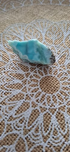 Avis d'un client : sa belle pierre larimar bleu clair posée sur un tissu à motifs.