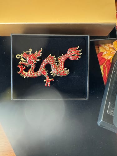Customer's red crystal 'Shimmering Dragon' Pin displayed inside its black presentation box.
