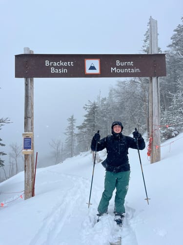 Reviewer smiling in deep snow while holding their Black Diamond Traverse Compactor Ski Poles on a mountain trail.