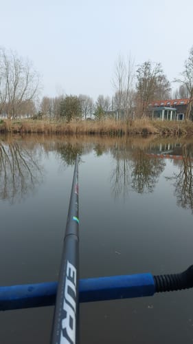 Klant toont de EURO MCX4-hengel in gebruik, uitgestrekt boven rustig water.