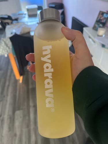 Customer holding a frosted water bottle filled with a yellow drink made from the Electrolyte Salts.