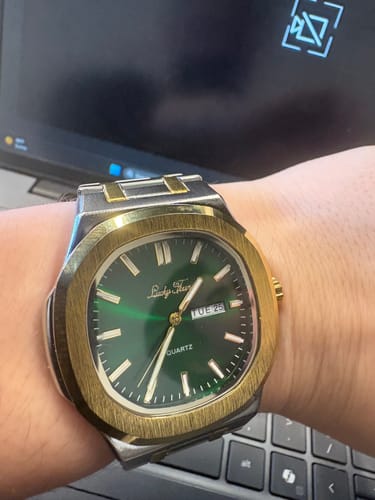 Customer's close-up of a two-tone watch with a green face on their wrist.