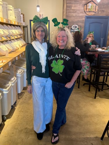 Customer with thick, curly hair smiling and posing with a friend indoors.