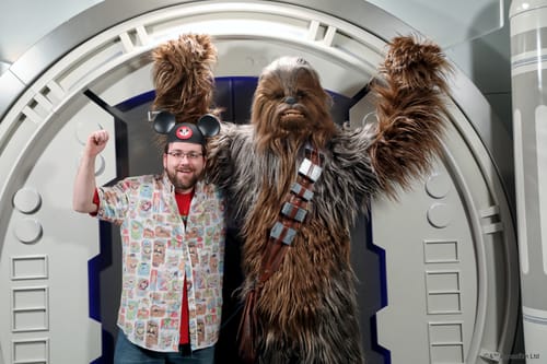 Customer at a theme park wearing the colorful 'Time to Meet the Muppets' shirt open over a red t-shirt.
