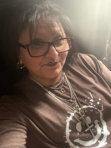 Close-up of a reviewer wearing her silver-colored Chicana Amor Chain layered with several other necklaces.