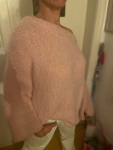Kunde trägt den flauschigen, übergroßen Cardigan 'CozyGlam' in Rosa.