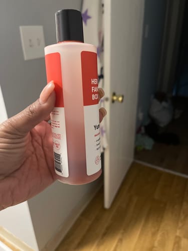 Customer holding the Yummy Organic Body Wash bottle, showing the red liquid inside.
