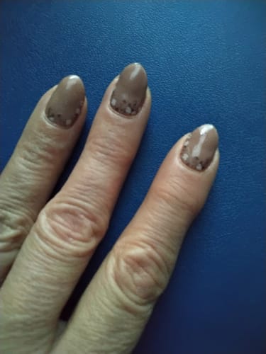Nahaufnahme der Hand einer Kundin, die die "Dainty Thoughts" UV-Gel-Nagelfolien in einem schönen Nude-Ton mit zartem Blumenmuster trägt.