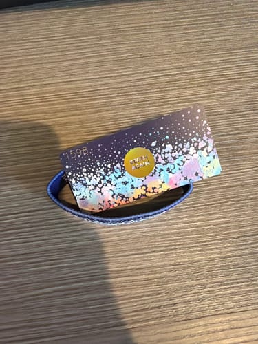 Customer's blue Begin Again Bracelet shown with its colorful packaging on a wooden surface.