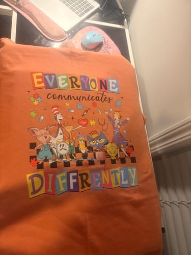 Customer shows a finished orange t-shirt with a colorful, detailed print made using the DTF Starter Bundle.
