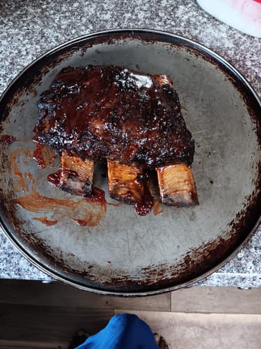 Customer's huge, sauce-covered USDA Choice Bone-In Short Ribs served on a round metal pan.