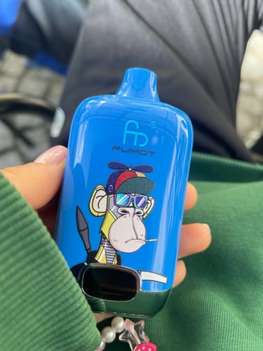 Ein Kunde hält die blaue ORIGINAL RANDM DIGITAL BOX 12000 Vape mit Cartoon-Grafik in der Hand.