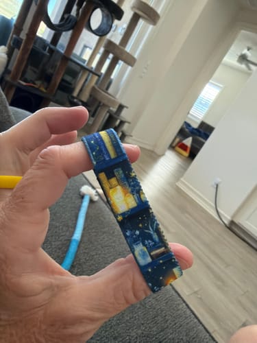 A customer holds up the Happy Place Bracelet, showing a detailed pattern of glowing books and stars on the dark blue fabric.