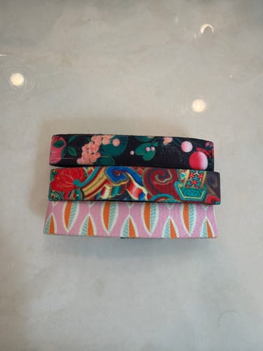Customer's three straps from the Non-Interactive Mystery 3-Pack, stacked to show their varied colorful patterns.