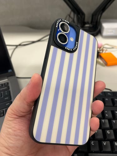 Customer holding the striped Coastal Breeze iPhone Case, shown with studded camera lens covers.