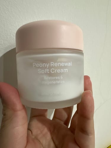 Customer holding the Peony Renewal Soft Cream in a frosted jar with a pink lid.