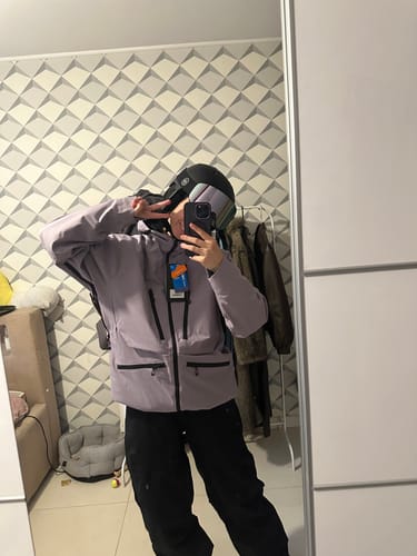 Reviewer posing for a mirror selfie wearing the purple snow jacket, black pants, and a ski helmet.