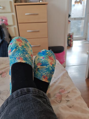Reviewer showing handmade house shoes made from the printed cotton fabric, featuring a colourful flamingo and leaf pattern.