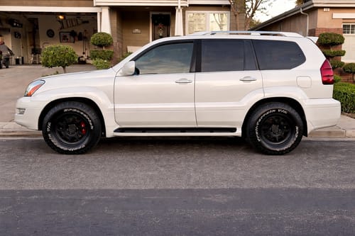 Customer's white SUV with 1.25" hubcentric wheel spacers and new black wheels, shown from the side on a residential street.