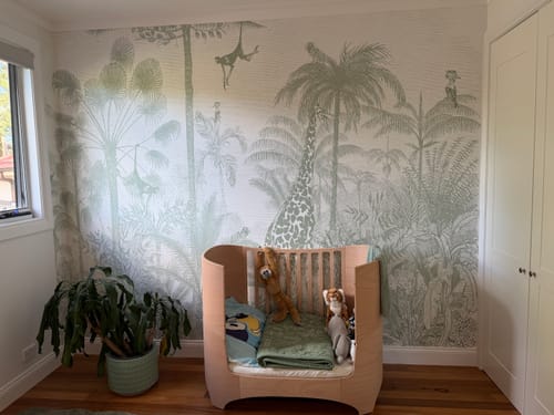 Reviewer's son's room featuring the Vintage Jungle in Khaki Wallpaper Mural as an accent wall behind a wooden crib.