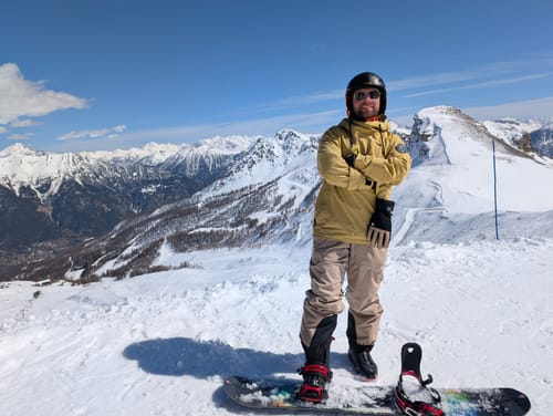 Reviewer wearing the baggy off white insulated snow pants on a snowy mountain.