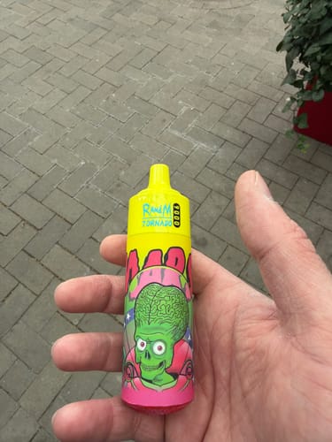 Customer's hand holding a colorful RandM 9000 Puffs disposable vape with a green alien design.