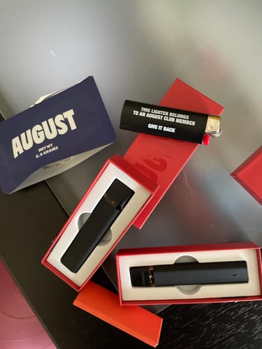 Customer's black August Lighter with white text, shown on a table with other August brand products.