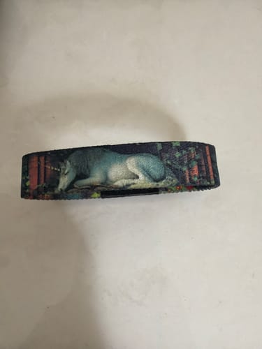 A close-up of the reviewer's Lost In The Pages Bracelet, featuring a unicorn resting in a forest.