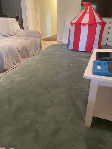 Customer's large, dark grey Mellow Mat in a living room next to a sofa and a child's tent.