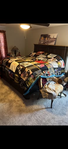 Customer's large Project Repat T-Shirt Quilt with colorful panels, spread across a bed in a bedroom.
