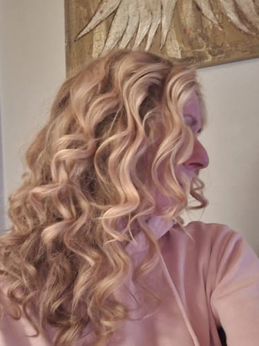 Eine Kundin zeigt ihr langes, gewelltes blondes Haar nach der Anwendung des Haarseifen-Sets.