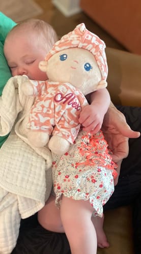 Customer's baby sleeping while cuddling the personalized Pudding Baby Girl doll.