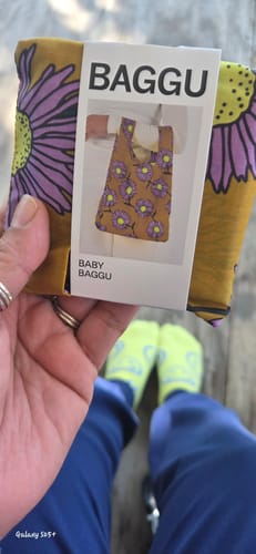 Customer holding their new Baby Baggu Daisy Chain bag, still folded in its original packaging sleeve.