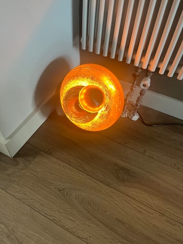 De Tafellamp Bira L van een klant staat aan en geeft een warme gloed op de houten vloer.