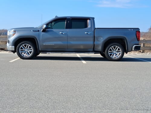 Customer's grey GM 1500 truck parked outside before the installation of lifted upper control arms.