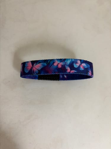 Customer's blue Change Is Beautiful Bracelet with a colorful butterfly pattern, laid flat on a white surface.