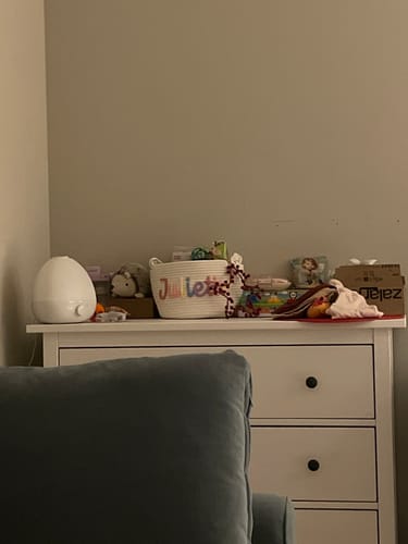 Reviewer's personalized white woven basket on a dresser, shown filled with toys.