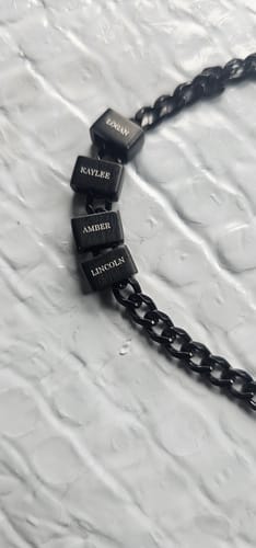 Customer's black Legacy necklace with four personalized beads engraved with the names: Logan, Kaylee, Amber, and Lincoln.