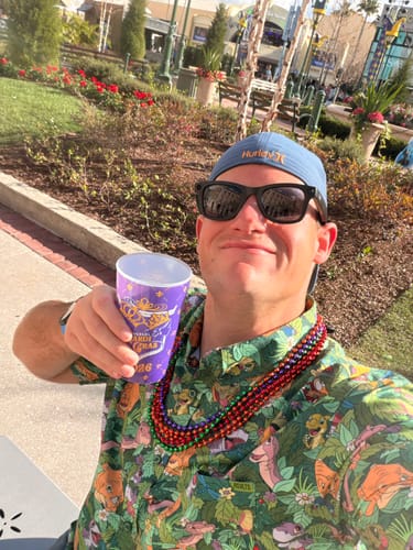 Customer wearing the patterned "Tree Star Adventures" shirt and festive beads outdoors.