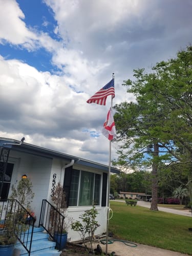 Customer's Florida flag flying below an American flag on a residential flagpole.