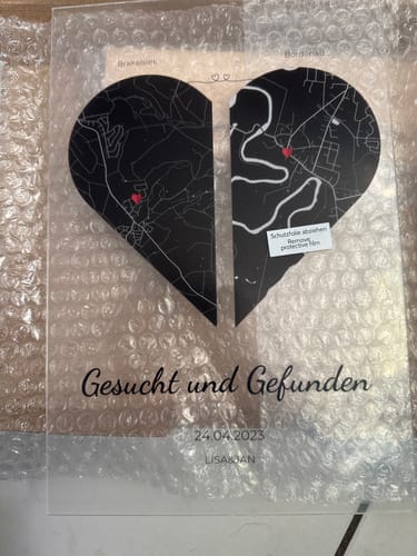 Kunde zeigt die personalisierte Acryltafel mit einem geteilten Herz aus zwei Karten und dem Text „Gesucht und Gefunden“.
